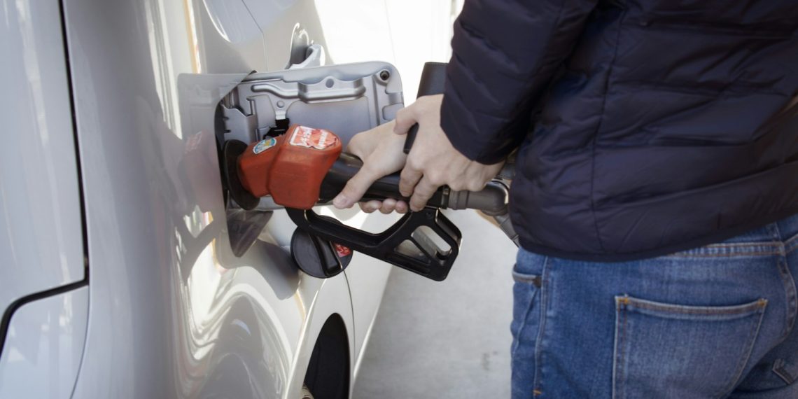 a man pumping gas into his car at a gas station