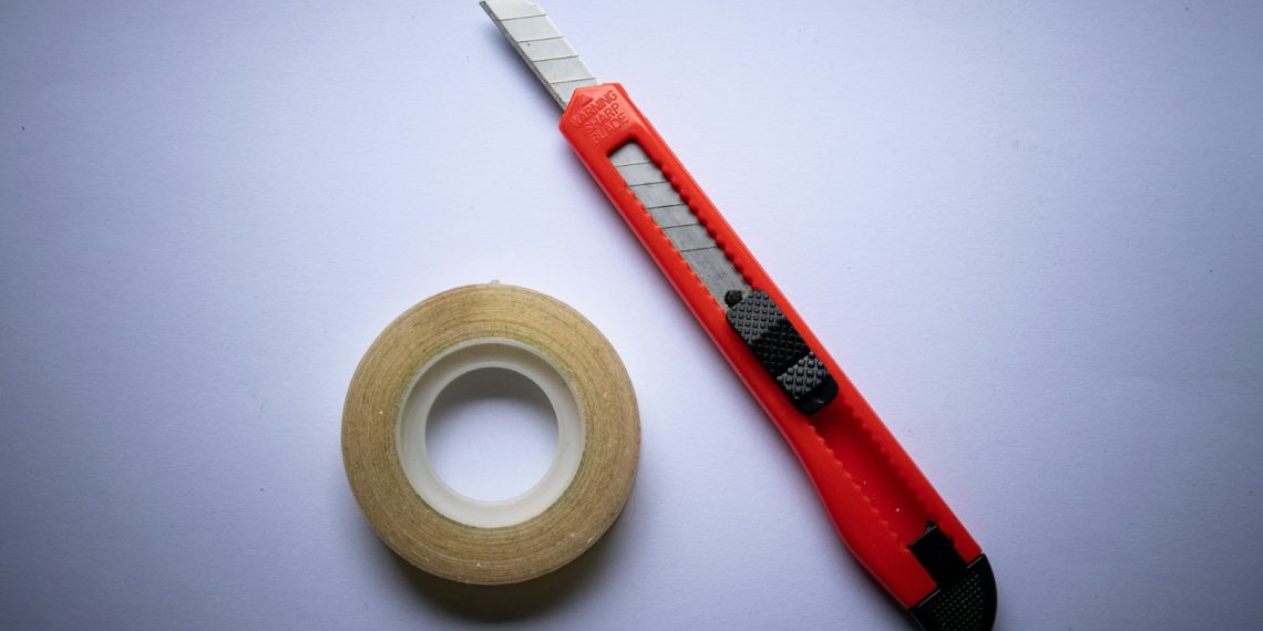 red and black click pen beside white tape roll