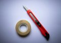 red and black click pen beside white tape roll