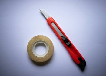 red and black click pen beside white tape roll