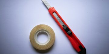 red and black click pen beside white tape roll