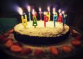 round Happy Birthday cake with lighted candles