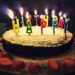 round Happy Birthday cake with lighted candles